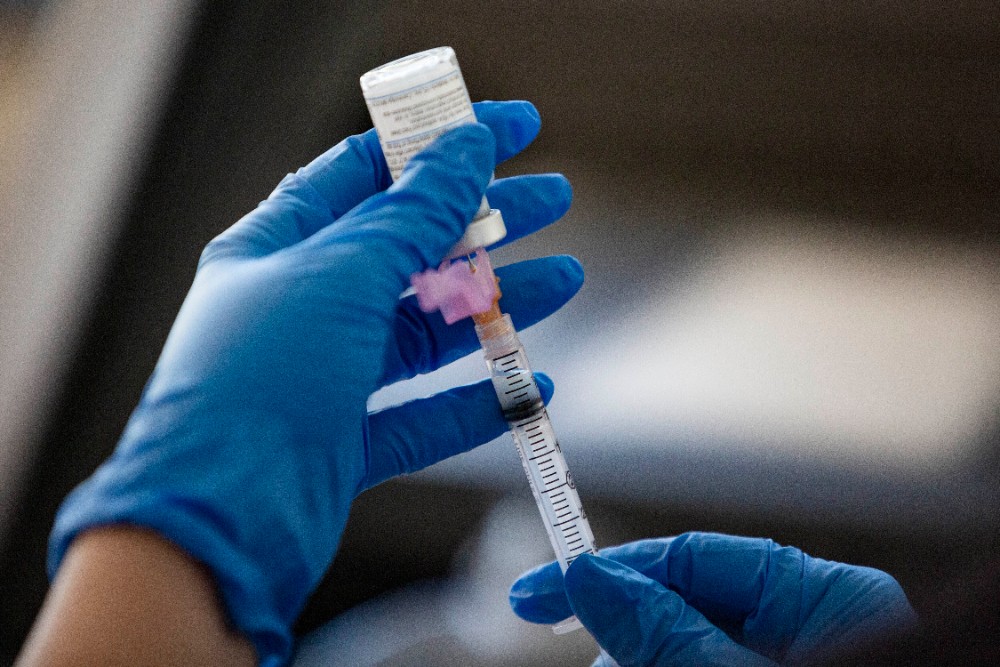 gloved hands hold vaccine bile and syringe