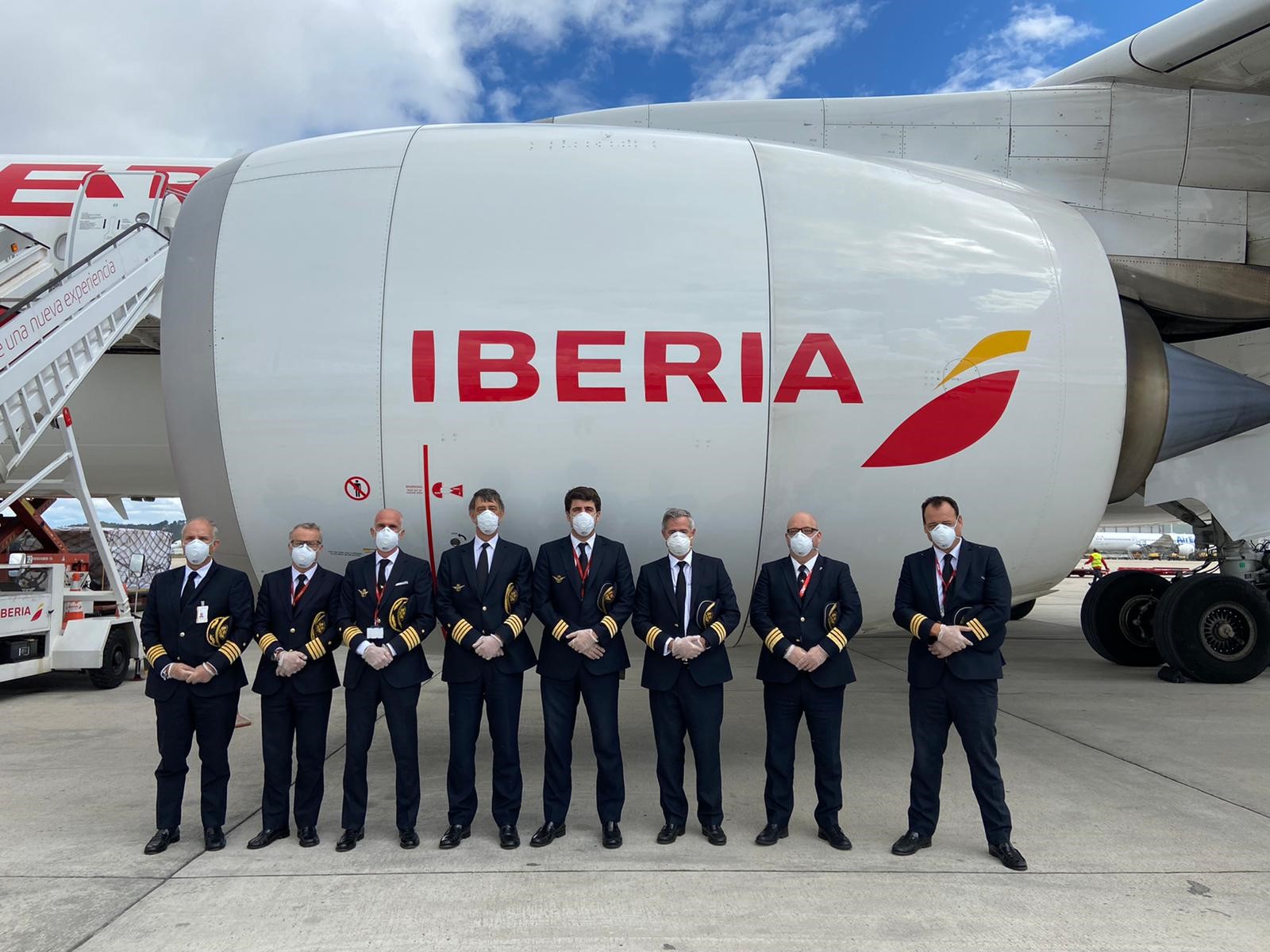 Iberia pilots standing next to a plane jet engine