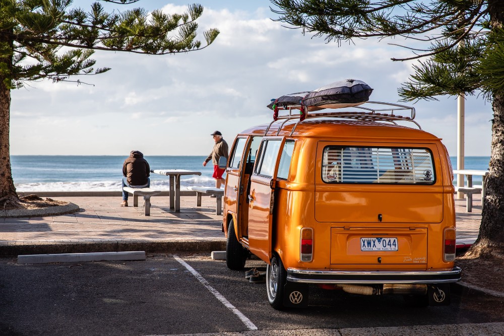 yellow VW van and people on a beach