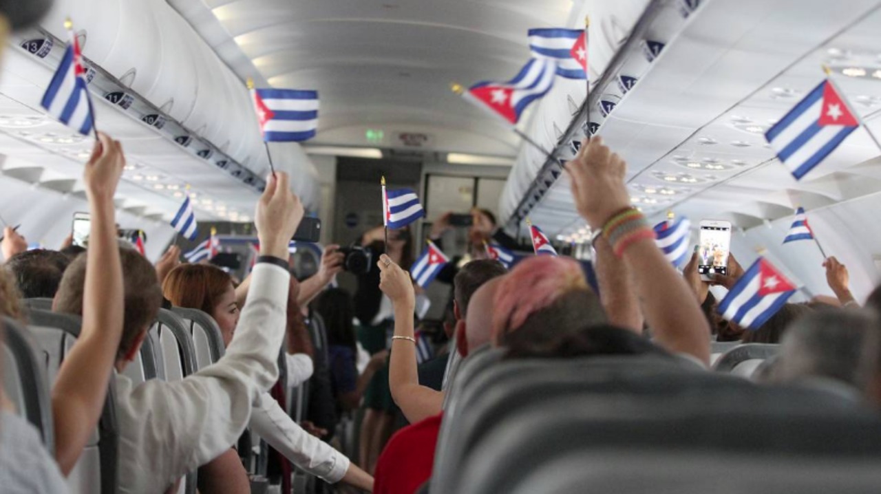 inside a Cuba flight, passengers with Cuban flags
