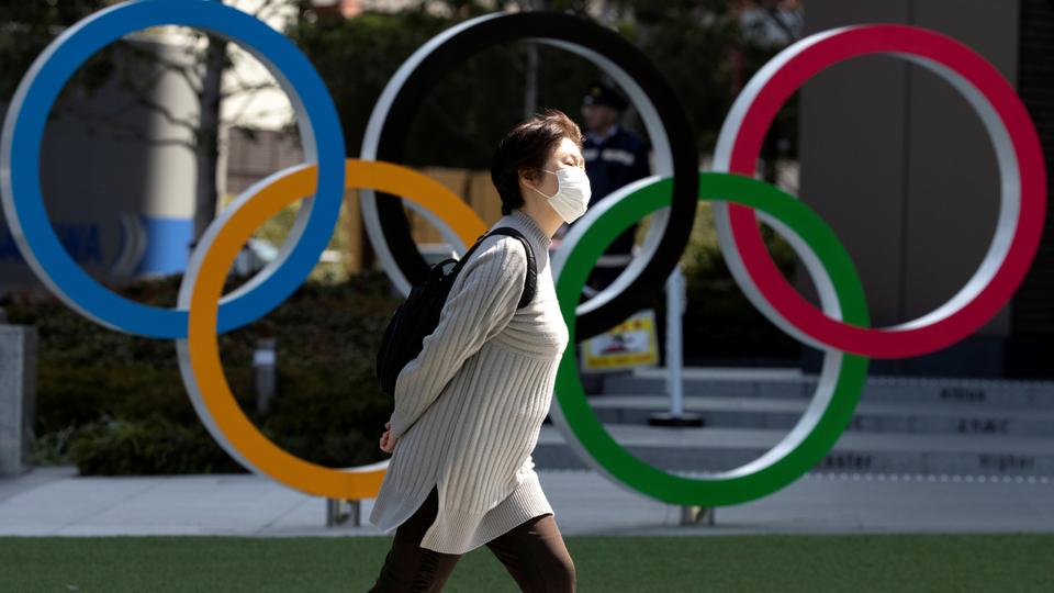 man walks in front of the five olympic rings
